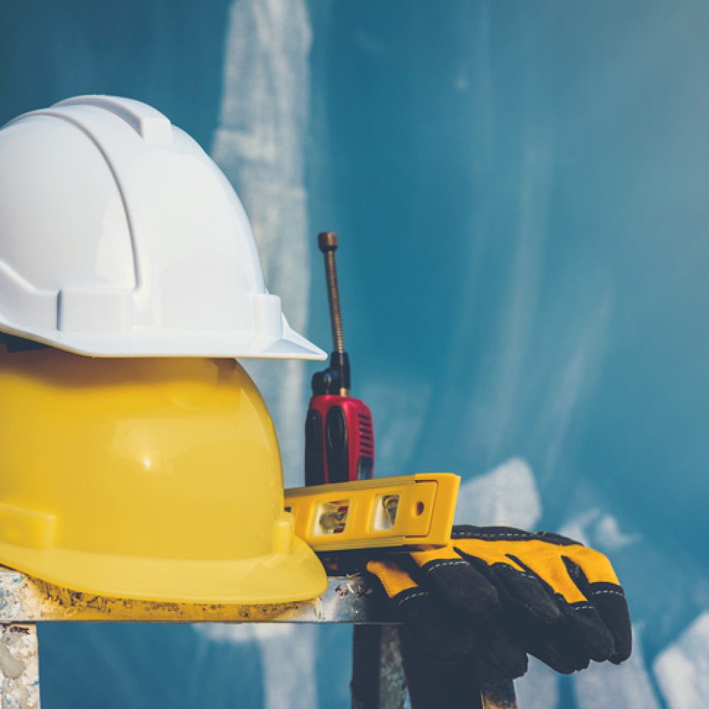 White and yellow helmet  with water level,gloves and radio that are placed on the folding ladder.